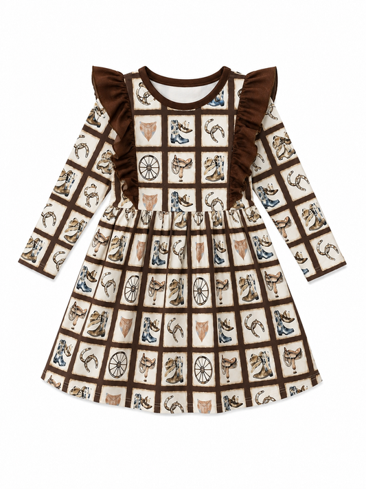 A long-sleeve baby dress with a brown and cream western-themed patchwork print featuring boots, horseshoes, and western icons, finished with ruffled shoulder details.